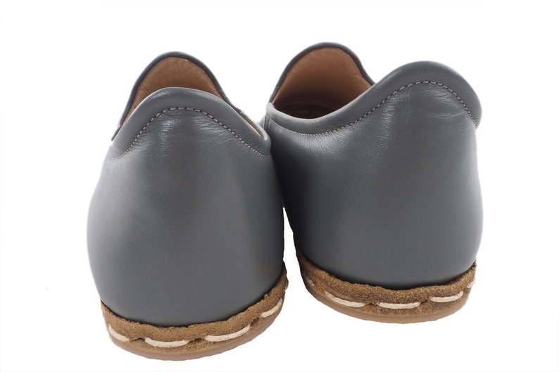 Peut inclure: Une paire de chaussures en cuir gris &agrave; enfiler avec une bordure cousue brune autour de la semelle.