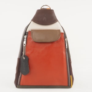 May include: A multi-colored leather backpack with a brown leather flap and a zippered pocket. The backpack has a brown leather strap and a silver zipper pull. The backpack is made of different colored leather panels, including brown, orange, beige, and green.