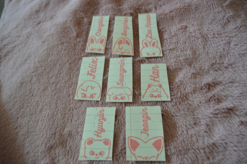 May include: Nine yellow sticky notes with pink text and illustrations of animals. The notes are labeled with the names:  Changbin, Bangchan, Lee Know, Felix, Seungmin, Han, Hyunjin, Jeongin.