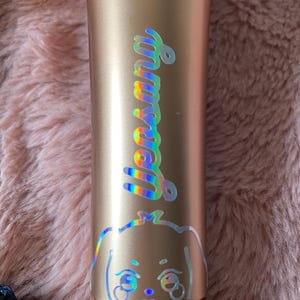 K&ouml;nnte beinhalten: Ein goldfarbenes Mikrofon mit einem holografischen Aufkleber, auf dem "Yena" steht, und einem Cartoon-Hund mit gro&szlig;en Augen.