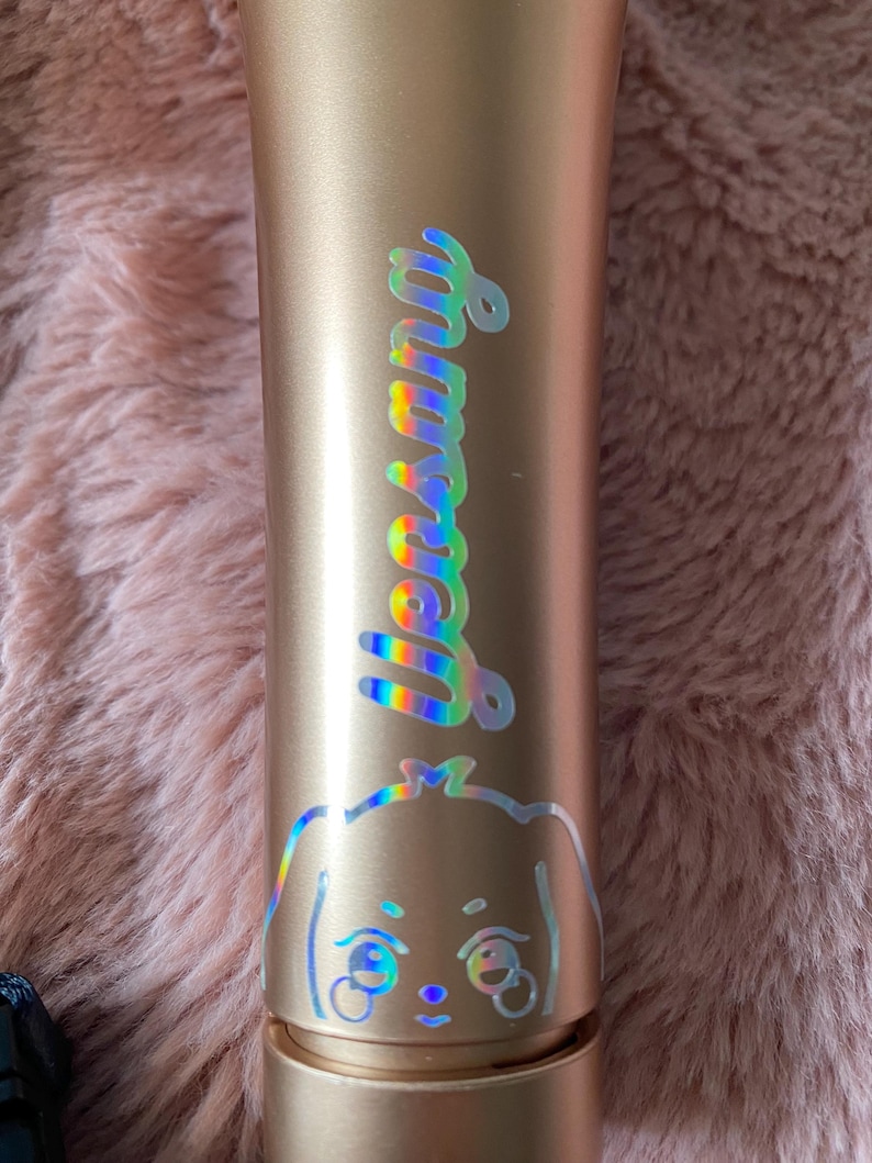 K&ouml;nnte beinhalten: Ein goldfarbenes Mikrofon mit einem holografischen Aufkleber, auf dem "Yena" steht, und einem Cartoon-Hund mit gro&szlig;en Augen.