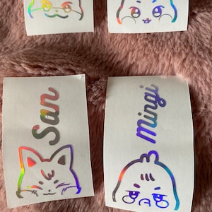 K&ouml;nnte beinhalten: Vier holografische Aufkleber mit Comic-Tiergesichtern und Namen. Die Aufkleber zeigen einen Hamster, ein Kaninchen, eine Katze und einen Vogel. Die Namen sind San, Min Yoongi und zwei weitere Namen, die nicht sichtbar sind.