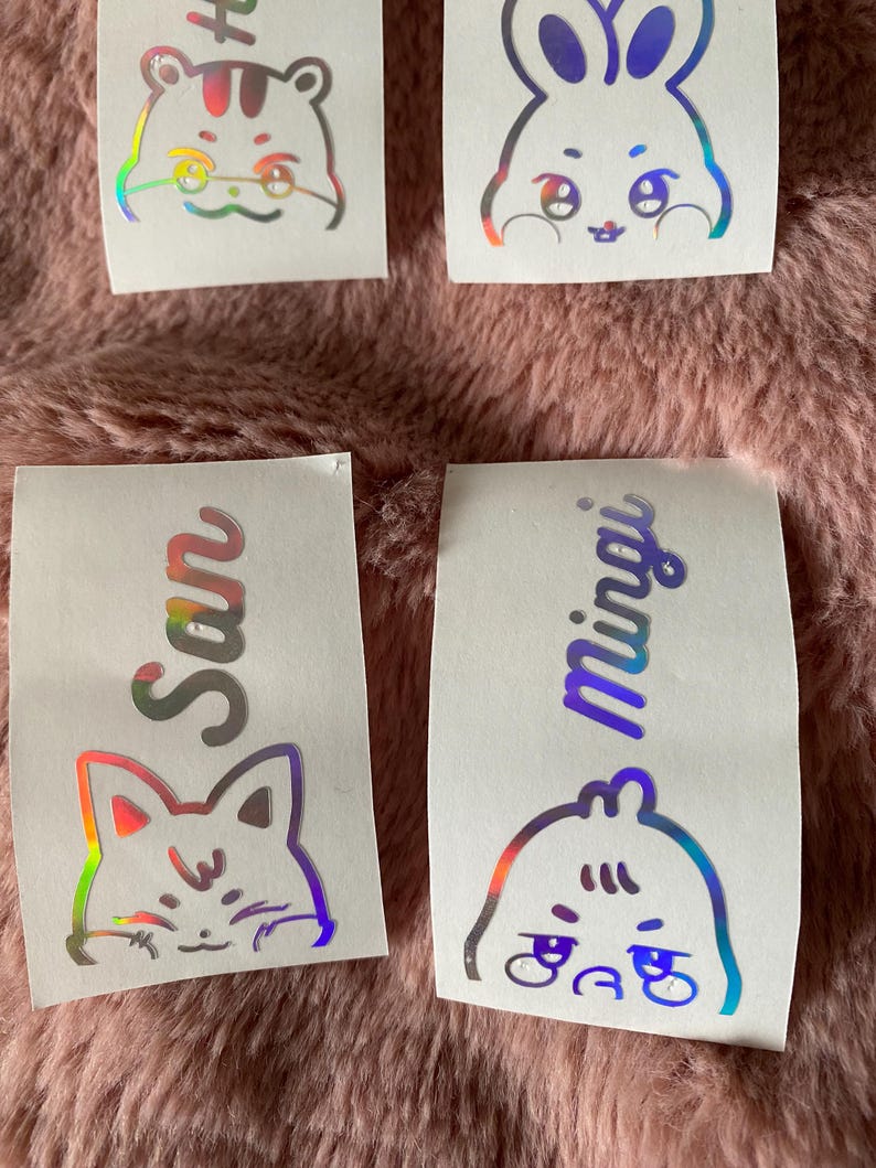 K&ouml;nnte beinhalten: Vier holografische Aufkleber mit Comic-Tiergesichtern und Namen. Die Aufkleber zeigen einen Hamster, ein Kaninchen, eine Katze und einen Vogel. Die Namen sind San, Min Yoongi und zwei weitere Namen, die nicht sichtbar sind.