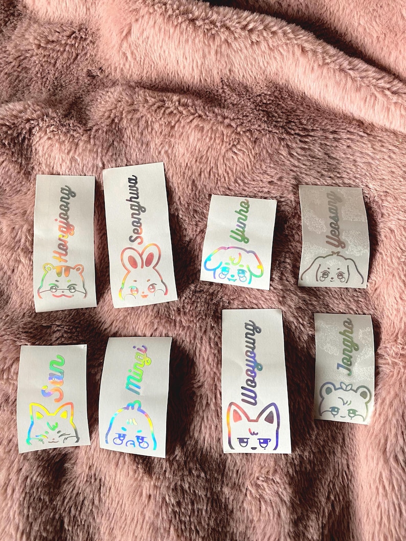 K&ouml;nnte beinhalten: Acht schimmernde holografische Aufkleber mit verschiedenen Tierillustrationen und Namen. Die Namen sind: 'Seonghwa', 'Yunho', 'Yeosang', 'Hongjoong', 'San', 'Mingi', 'Wooyoung' und 'Jongho'.