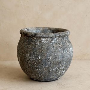 May include: A round, bulbous pot with a thick, rolled rim. The exterior surface features a heavily textured, mottled finish in shades of dark gray, charcoal, and silver, creating a weathered, stone-like appearance with visible depth and variation.