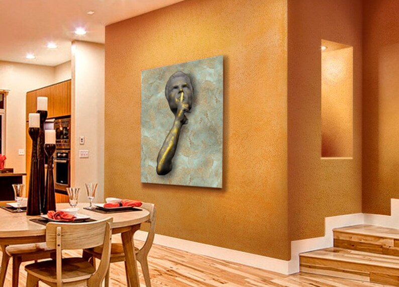 May include: A gold-toned sculpture of a person with their finger to their lips, suggesting silence. The sculpture is mounted on a textured, light blue background.