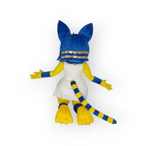 May include: A plush mascot costume of a yellow cat with blue ears and a blue and gold headpiece. The costume is wearing a white dress and has a blue and yellow striped tail.