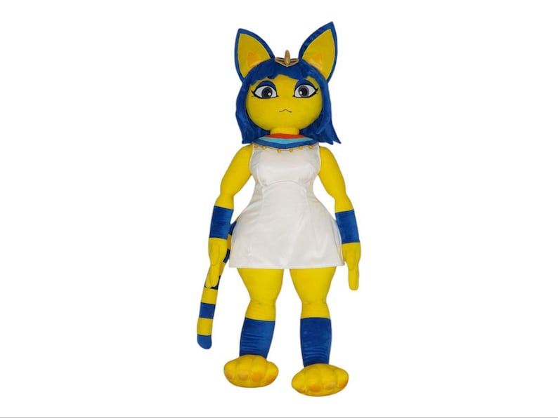 May include: A plush toy shaped like a cat with blue hair, wearing a white dress and blue leg warmers. The toy has yellow fur and a gold collar.