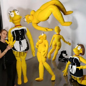 May include: A collection of large, yellow plush figures resembling characters from a popular animated sitcom. One figure is dressed in a maid outfit, while others are in various poses. The figures have black eyelashes and red necklaces.