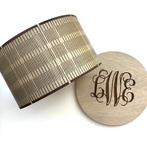May include: A wooden box with a decorative lid and a monogrammed base. The lid has a geometric pattern and the base has the letters "LVE" engraved in a script font.