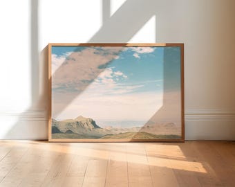 Puede incluir: Una fotografía enmarcada de una cordillera con un cielo azul y nubes blancas. Las montañas son verdes y marrones, y el cielo es azul claro con nubes blancas.