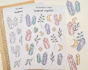 May include: A sheet of stickers featuring various pastel-colored crystals, moons, stars, and leaves. The text "The Aesthetics Studio magical crystals" is printed at the top of the sheet.