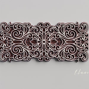 May include: A brown wooden decorative wall art piece with a white intricate floral design. The design features a central flower with swirling patterns and leaves.