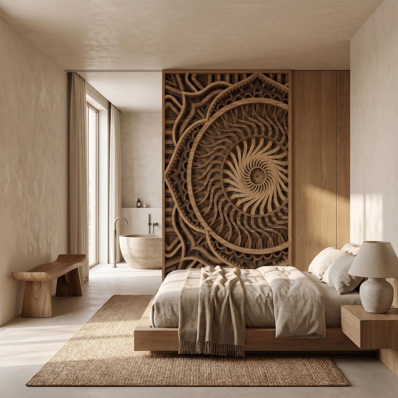 May include: A large, circular, multi-layered wooden wall art piece with intricate, radiating geometric patterns serves as a room divider between a bedroom and a bathroom, featuring a low-profile bed, a wooden bench, and a bedside lamp.