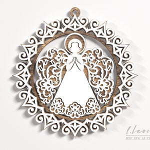 May include: White wooden angel ornament with a lacy design. The angel is in a praying position with its hands clasped together. The ornament is surrounded by a circular frame with a lacy design.