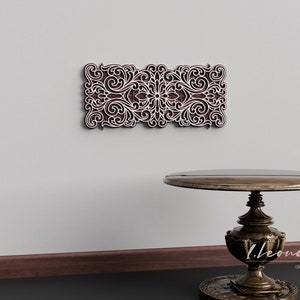 May include: A white wall with a brown wooden decorative wall panel featuring a carved floral design. A dark brown wooden table with a round top and a pedestal base sits in front of the wall.