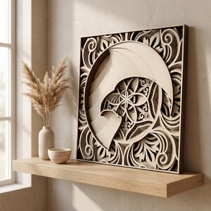 May include: A square, multi-layered wooden wall art piece featuring a laser-cut design of a crescent moon and a central geometric flower pattern surrounded by intricate, swirling filigree motifs in natural light wood tones.
