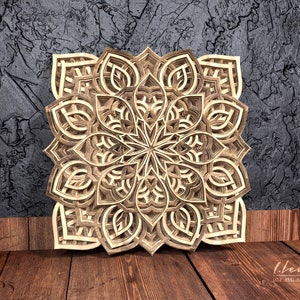 May include: A detailed wooden mandala with intricate cutouts, creating a geometric pattern. The mandala is light brown and has a symmetrical design.