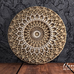 K&ouml;nnte beinhalten: Ein mehrschichtiges Holzmandala mit detailliertem, symmetrischem Design. Das kreisf&ouml;rmige Kunstwerk weist konzentrische Muster in Beige- und Braunt&ouml;nen auf und erzeugt einen dreidimensionalen Effekt. Der Hintergrund ist eine dunkle, strukturierte Oberfl&auml;che.