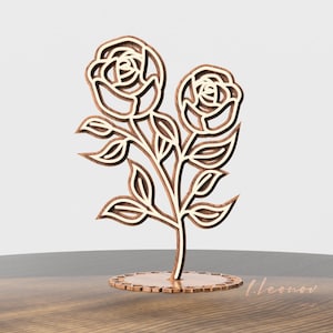 May include: A wooden rose bouquet with two roses and leaves, standing on a circular base. The roses are cut out and have a white interior.