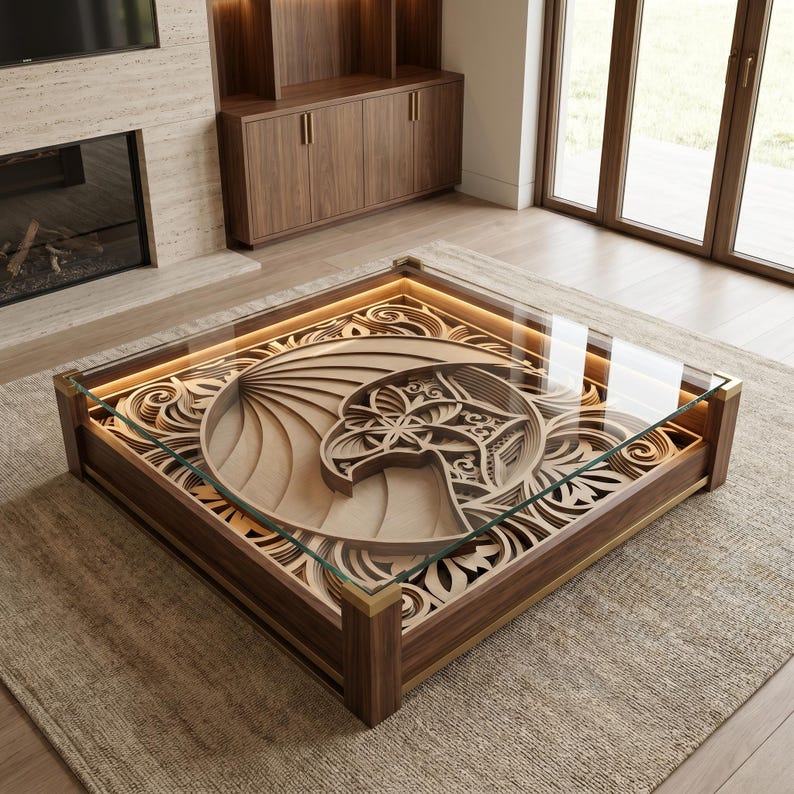 May include: A square coffee table with a dark wood frame and a glass top. Beneath the glass, a multi-layered wooden carving features an intricate eagle head design surrounded by swirling patterns, illuminated by integrated warm LED lighting.