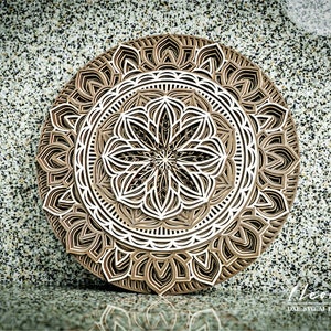 May include: A brown and white layered mandala design with intricate details. The mandala is made of paper and is perfect for laser cutting.