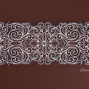 May include: An intricate white design with a floral pattern on a brown background. The design is symmetrical and features a repeating pattern of swirls and leaves. The design is framed by a white border.