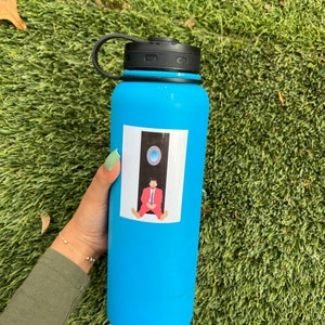 May include: A blue reusable water bottle with a black lid and a sticker of a man sitting in a doorway with a blue circle above him.