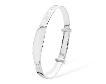 May include: A silver baby bangle with a scalloped edge and an inscription that reads "ABC 123".