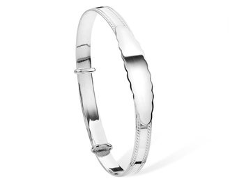 May include: A silver baby bangle with a scalloped edge and a blank plate for engraving.