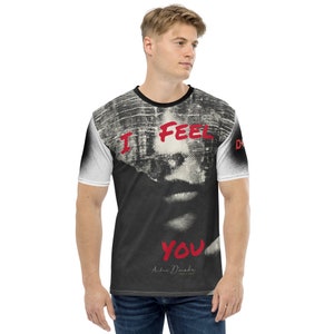 Könnte beinhalten: Ein schwarz-weißes T-Shirt mit einem Grafikdruck eines Frauen Gesichts und dem Text "I FEEL YOU" in Rot. Der Text "Andre Donade" ist in Gold am unteren Rand des Shirts geschrieben.