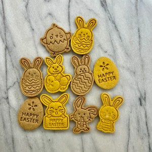 May include: Nine Easter-themed cookies, including bunnies, chicks, and eggs, decorated with icing and the words "Happy Easter".
