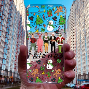 May include: A clear phone case with a Christmas-themed design featuring characters from the movie. The case has a white background with green, red, and yellow accents.