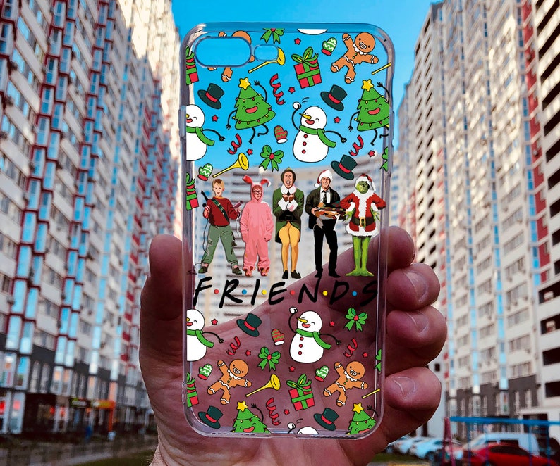 May include: A clear phone case with a Christmas-themed design featuring characters from the movie. The case has a white background with green, red, and yellow accents.