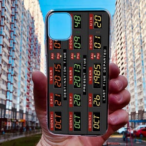 May include: A black phone case with a digital display showing the date and time. The display shows "MONTH OCT DAY 21 YEAR 2015" and "LAST TIME DEPARTED 1985".