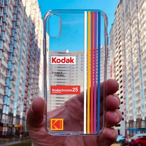 May include: Clear phone case with a 25 film cartridge design. The case has a rainbow stripe design and the text "super 8 cartridge" and "25 color film".