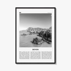 May include: A black and white framed wall art print featuring a coastal landscape of Devon, England. The image shows rocky cliffs meeting the sea, with text at the top reading DV and ENGLAND, UK, and a descriptive paragraph below titled DEVON.