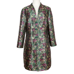 Puede incluir: Una chaqueta verde de manga larga con un estampado floral en tonos de rosa, dorado y verde. La chaqueta tiene un cuello mandarín y cierre de botones.