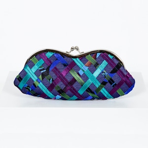 Può includere: Una pochette con chiusura argentata, con un motivo a righe blu, viola e verde.