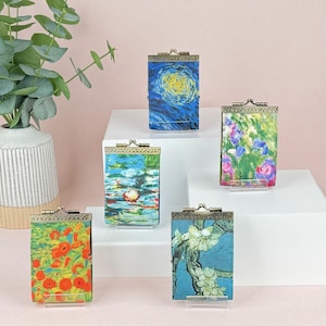 May include: Five small, rectangular metal-framed cases with clasps, each featuring a famous painting reproduction. The artworks include Van Gogh's "Starry Night", Monet's "Water Lilies", and other floral and landscape scenes.