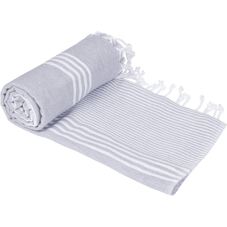 May include: A gray and white striped Turkish towel with fringe. The towel is rolled up and has a white stripe running down the center.