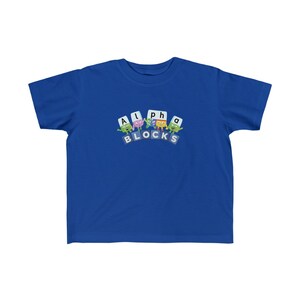 May include: A royal blue youth t-shirt featuring a graphic of colourful alphabet blocks spelling "Alpha Blocks".