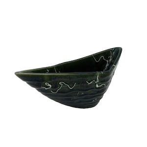 Op de afbeelding: Een donkergroene keramische kom met een golvend, getextureerd oppervlak en witte swirl-ontwerpen. De kom is gevormd als een boot.