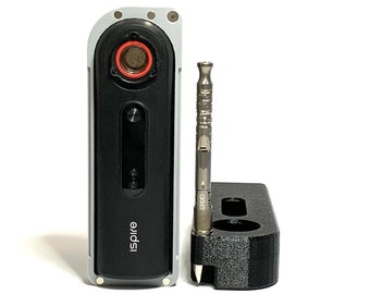 May include: A silver and black electronic vaporizer with a red ring around the mouthpiece. The vaporizer is sitting on a black stand with a silver tool next to it. The vaporizer has the word "Inspire" printed on the side.