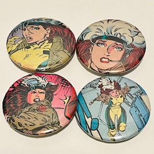 May include: Four circular pin-back buttons featuring comic book illustrations of a character with brown hair and a white streak. Each button displays a different action pose or close-up of the character wearing a yellow and green suit.