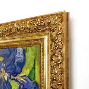 以下が含まれることがあります： 緑色の背景に青いアイリスを描いた額入りの絵画。アートワークは金色の装飾フレームに入っています。絵画は筆致と鮮やかな色使いが特徴で、花を詳細に表現しています。
