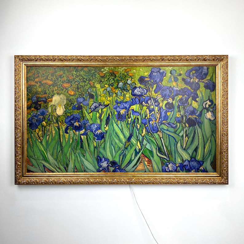 Puede incluir: Una impresi&oacute;n enmarcada de la pintura "Lirios" de Vincent van Gogh. La obra presenta vibrantes lirios azules con hojas verdes, sobre un fondo de jard&iacute;n. El marco es ornamentado, con un acabado dorado.
