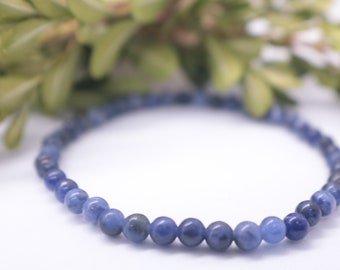 May include: A blue gemstone bracelet made of small, round beads. The bracelet is on a white background.