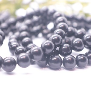 May include: A strand of black round beads, likely made of onyx or obsidian, for jewelry making.
