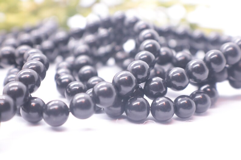 May include: A strand of black round beads, likely made of onyx or obsidian, for jewelry making.